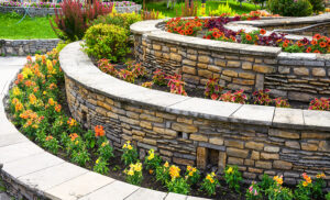 Residential backyard with gorgeous landscape design featuring flower beds and stone retaining walls created by hardscape contractors