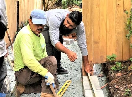 Allentuck landscaping team installing stone pavers and checking level