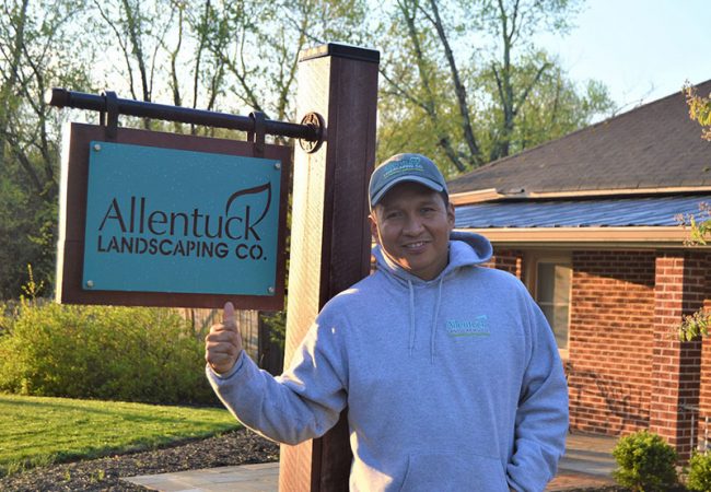 Allentuck landscaping Cruz Reynaldo standing beside metal sign